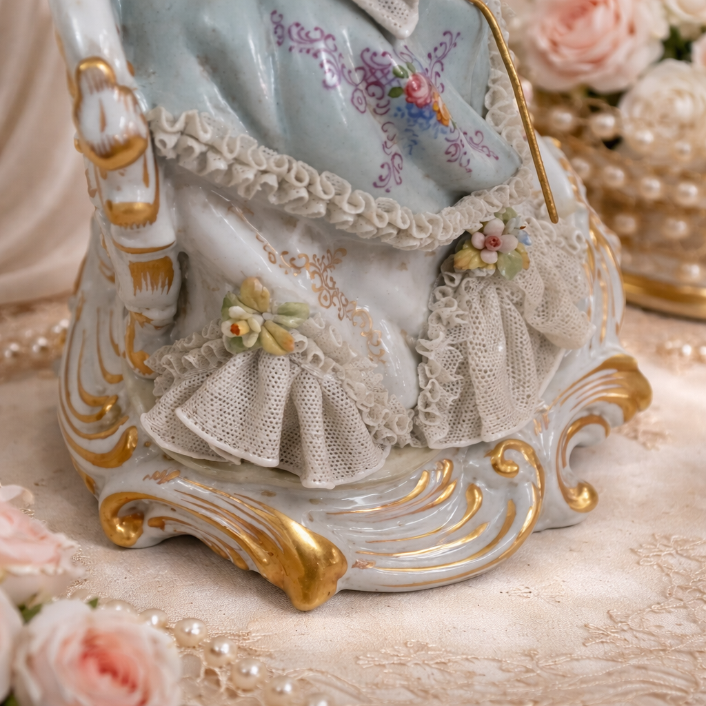 Scultura in porcellana policroma finemente modellata, raffigurante dama in abiti settecenteschi seduta su elegante seduta rocaille. La figura, di gusto rococò, è impreziosita da ricchi decori floreali applicati, delicati motivi dipinti e abbondanti dorature, con accurata resa dei merletti, dei panneggi e dell’acconciatura. La base sagomata, mossa e dorata, completa armoniosamente la composizione. Produzione Capodimonte, Italia, XX secolo, come da marchio al verso; oggetto decorativo di pregio, in buono stato di conservazione.