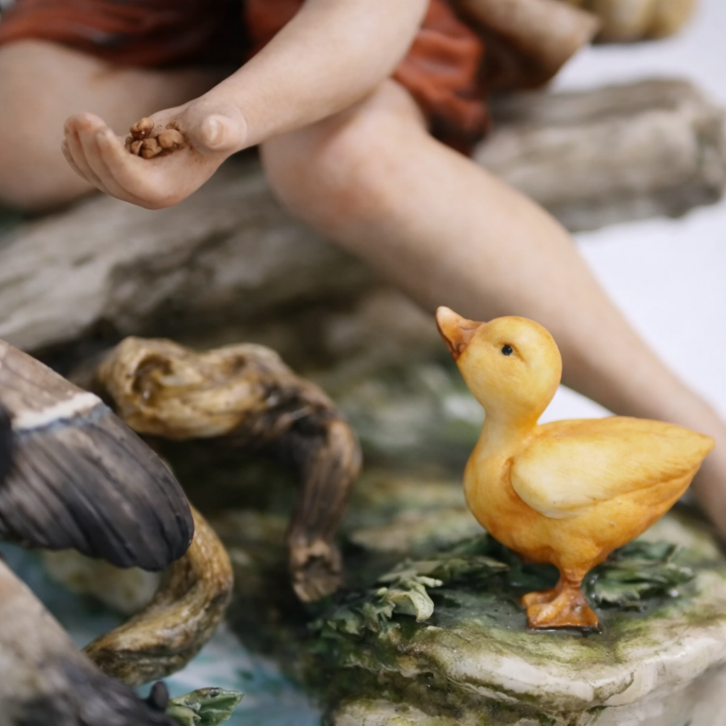 Statuina in porcellana policroma raffigurante giovane pescatore seduto in ambiente naturalistico con volatili acquatici, tronco e vegetazione modellati a rilievo. Buona qualità esecutiva, con accurata resa dei dettagli e cromie ben sfumate. Produzione italiana del XX secolo, ambito Capodimonte, come da firma dipinta alla base. In buono stato di conservazione, decorativa e collezionabile.