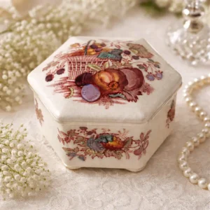 Scatolina esagonale in ironstone inglese, manifattura Mason’s, decorata con motivo policromo “Fruit Basket” raffigurante cesto di frutta e composizioni naturalistiche. Smalto color avorio con stampa in rosso, marrone e tocchi policromi. Marchio al fondo “Mason’s Patent Ironstone – Fruit Basket – Made in England”, databile alla prima metà del XX secolo. In buono stato di conservazione, con lievi segni d’uso e usura sul fondo.