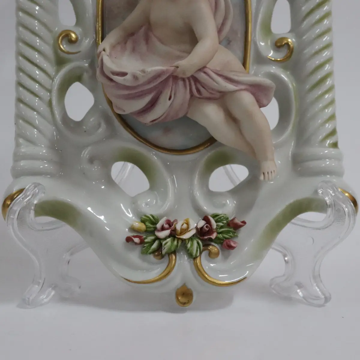 Coppia di acquasantiere da parete in porcellana policroma, in stile rococò, con struttura traforata a volute e dorature a rilievo. Al centro, putti modellati a tutto tondo con drappi azzurro e rosato entro riserva ovale. Vaschetta inferiore integrata, decorata con fiori applicati. Produzione italiana Capodimonte, XX secolo, come da marchio con N coronata e firma Corti. In buono stato di conservazione, pregevoli per arredo devozionale e collezione.