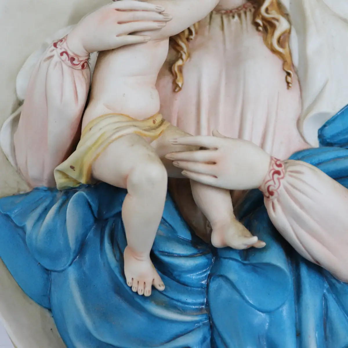 La Madonna con Bambino in porcellana di Capodimonte è un capolavoro artistico, firmato dal Maestro Corti. Quest’opera ovale da parete viene comunemente chiamata Capezzale, creata negli anni ’90 e originariamente distribuita dalla celebre manifattura artigianale King’s, ormai chiusa, è una rarità molto ricercata dai collezionisti di arte sacra. Il bassorilievo rappresenta una scena piena di dolcezza e armonia. La cura nei dettagli si riflette nella perfetta lavorazione delle mani e dei piedi del Bambino, mentre i volti sono stati delicatamente dipinti. I colori decisi e sfumati, con predominanza di azzurro, turchese e rosa. L’ovale è finemente decorato lateralmente con eleganti rifiniture in oro, che rende questa porcellana un’opera d’arte di pregio. La combinazione di dettagli raffinati e l’abilità manuale degli artigiani fanno di questa creazione una rappresentazione perfetta della porcellana di Capodimonte, che da sempre è sinonimo di alta qualità artistica e artigianale. Misure: cm. 47 x 35 x 5 Condizioni perfette