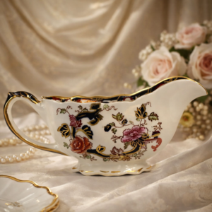 Salsiera in fine porcellana inglese Mason’s, linea Mandalay, caratterizzata da elegante forma sagomata con beccuccio e manico, decorata con raffinati motivi floreali policromi arricchiti da elementi in blu cobalto e abbondanti dorature. Bordo mosso profilato in oro. Marchio al fondo “Mason’s – Patent Ironstone – Mandalay – Made in England”. Produzione del XX secolo. Oggetto di gusto classico, decorativo e da collezione, in buono stato di conservazione.