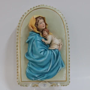 Porcellana di Capodimonte – Madonna con Bambino Ovale da Parete  La Madonna con Bambino in porcellana di Capodimonte è un capolavoro artistico, firmato dal Maestro Corti. Quest’opera ovale da parete viene comunemente chiamata Capezzale, creata negli anni ’90 e originariamente distribuita dalla celebre manifattura artigianale King’s, ormai chiusa, è una rarità molto ricercata dai collezionisti di arte sacra. Il bassorilievo rappresenta una scena piena di dolcezza e armonia. La cura nei dettagli si riflette nella perfetta lavorazione delle mani e dei piedi del Bambino, mentre i volti sono stati delicatamente dipinti. I colori decisi e sfumati, con predominanza di azzurro, turchese e rosa. L’ovale è finemente decorato lateralmente con eleganti rifiniture in oro, che rende questa porcellana un’opera d’arte di pregio. La combinazione di dettagli raffinati e l’abilità manuale degli artigiani fanno di questa creazione una rappresentazione perfetta della porcellana di Capodimonte, che da sempre è sinonimo di alta qualità artistica e artigianale. Condizioni perfette