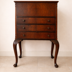 Raffinato sewing cabinet / mobiletto da lavoro inglese dei primi del Novecento, realizzato in legno massello e impiallacciato con bella venatura a specchio sul fronte. Dotato di tre cassetti e piano superiore apribile che nasconde un vano organizzato per il cucito con scomparti interni e rivestimenti in tessuto rosa. Sostenuto da eleganti gambe mosse in stile Queen Anne, presenta linee armoniose e proporzioni equilibrate. Mobile solido, ben conservato, con piacevole patina del tempo. Perfetto come complemento d’arredo o pezzo da collezione.