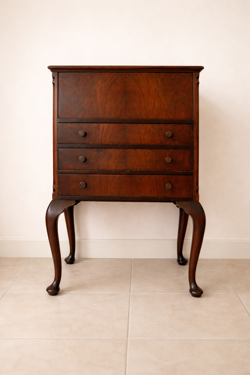 Raffinato sewing cabinet / mobiletto da lavoro inglese dei primi del Novecento, realizzato in legno massello e impiallacciato con bella venatura a specchio sul fronte. Dotato di tre cassetti e piano superiore apribile che nasconde un vano organizzato per il cucito con scomparti interni e rivestimenti in tessuto rosa. Sostenuto da eleganti gambe mosse in stile Queen Anne, presenta linee armoniose e proporzioni equilibrate. Mobile solido, ben conservato, con piacevole patina del tempo. Perfetto come complemento d’arredo o pezzo da collezione.