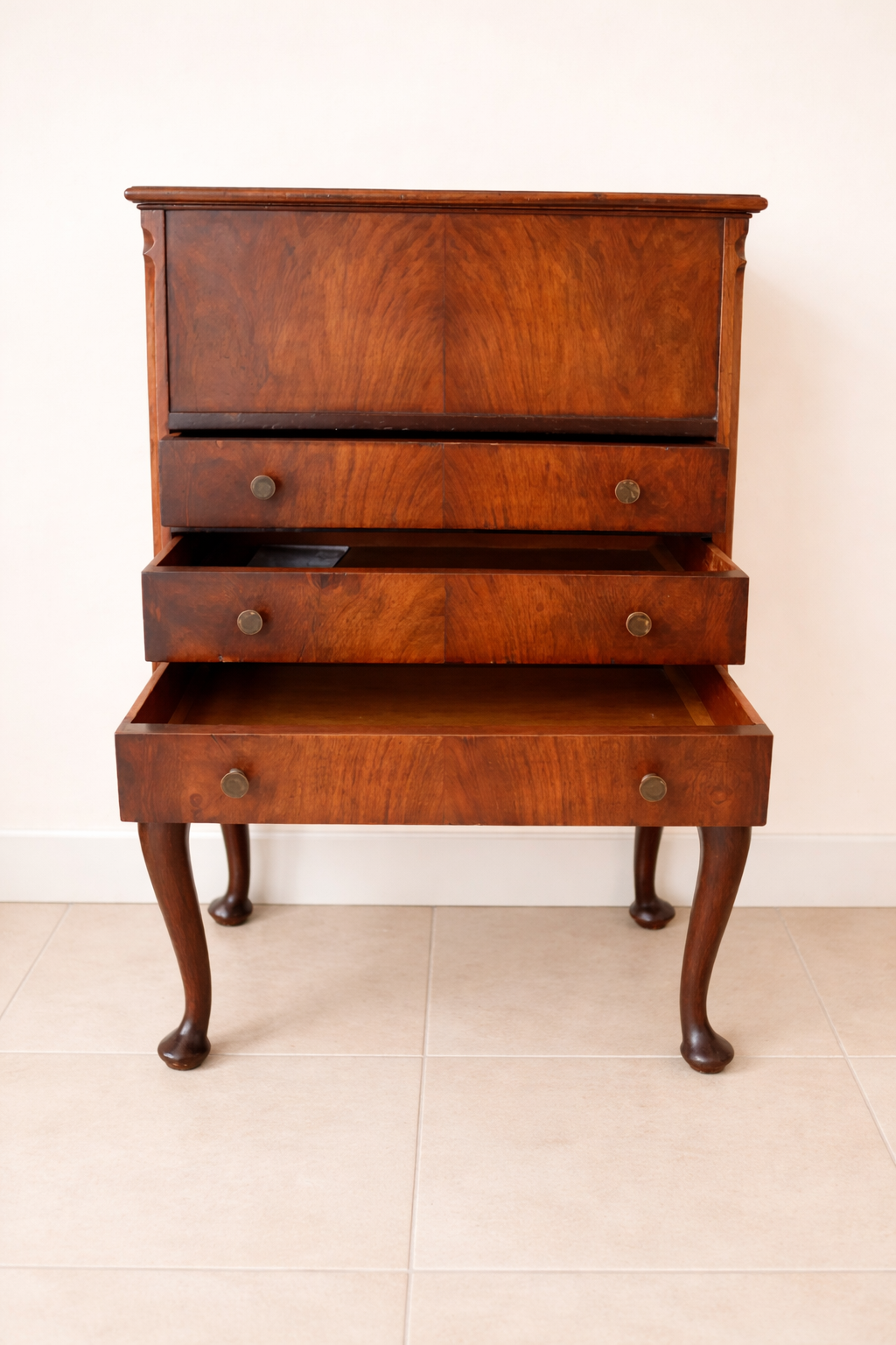 Raffinato sewing cabinet / mobiletto da lavoro inglese dei primi del Novecento, realizzato in legno massello e impiallacciato con bella venatura a specchio sul fronte. Dotato di tre cassetti e piano superiore apribile che nasconde un vano organizzato per il cucito con scomparti interni e rivestimenti in tessuto rosa. Sostenuto da eleganti gambe mosse in stile Queen Anne, presenta linee armoniose e proporzioni equilibrate. Mobile solido, ben conservato, con piacevole patina del tempo. Perfetto come complemento d’arredo o pezzo da collezione.