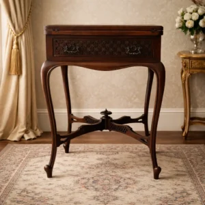 Tavolo da gioco / tavolino da salotto trasformabile, in legno massello, riconducibile alla produzione inglese seconda metà del 19° secolo, di gusto eclettico con richiami Luigi XV / Luigi XVI rivisitati. Il mobile presenta una struttura elegante e slanciata, poggiante su quattro gambe mosse leggermente arcuate, raccordate inferiormente da una croce centrale sagomata con raffinati intagli traforati a motivi geometrici, culminante in un elemento tornito centrale di grande equilibrio formale e qualità esecutiva. La fascia sottopiano è arricchita da pannelli intagliati a traforo con motivo floreale ripetuto, di gusto neorinascimentale, al cui centro sono applicate maniglie originali in bronzo fuso, finemente lavorate con volute e motivi vegetali. Le ferrature appaiono coeve al mobile. Il piano superiore è apribile e trasformabile: tramite un sistema a quattro ante ribaltabili incernierate, il tavolo si apre rivelando un piano da gioco rivestito in panno verde, tipico dei tavoli da carte o da gioco da salotto dell’epoca. Sulle ante esterne sono presenti incassi circolari (porta bicchieri o segnapunti), elemento funzionale e decorativo, indice di una destinazione d’uso conviviale e aristocratica. Le cerniere e i meccanismi di apertura sono in metallo, solidi e ben conservati, coerenti con la manifattura storica del mobile. La patina del legno è calda e uniforme, con normali segni del tempo compatibili con l’età, che ne confermano l’autenticità senza comprometterne la leggibilità estetica. Si tratta di un mobile da salotto di pregio, pensato per ambienti borghesi o aristocratici, destinato all’intrattenimento (giochi di carte, conversazione). La qualità dell’intaglio, l’eleganza delle proporzioni e la presenza del piano trasformabile ne fanno un oggetto ricercato, apprezzabile sia come tavolo funzionale sia come elemento d’arredo di rappresentanza. Misure: Altezza cm. 71  Larghezza cm. 53 x 53