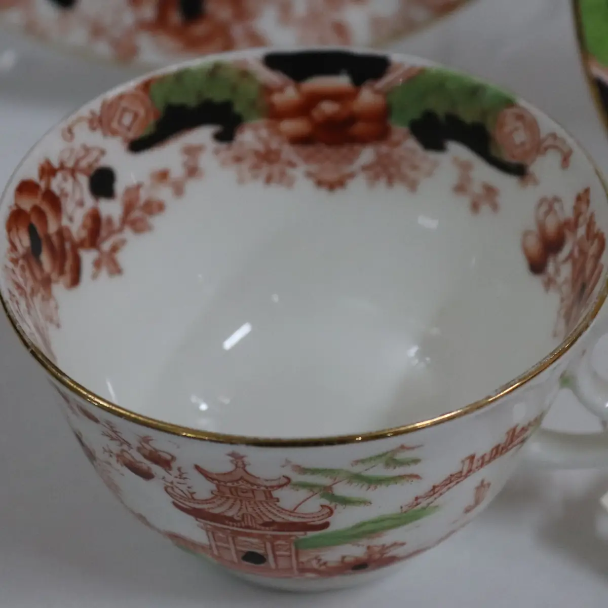 Set da tè inglese in ironstone Atlas China, Stoke-on-Trent, composto da piatti e tazza, decorato in stile chinoiserie con pagode, fiori e motivi orientali in tonalità rosso ruggine, verde e nero, con profili in oro. Produzione fine ottocento, primo Novecento. In buone condizioni generali. Elegante insieme da collezione e da esposizione.