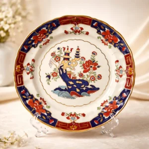 Piatto da dolce in ironstone inglese Mason’s, serie Red Pagoda, appartenente alla Heritage Plate Collection, edizione limitata numerata (1997). Decorazione in stile orientale con pagode, paesaggio e ricca bordura rosso mattone, blu e oro. In ottime condizioni generali. Elegante pezzo da collezione decorativo.