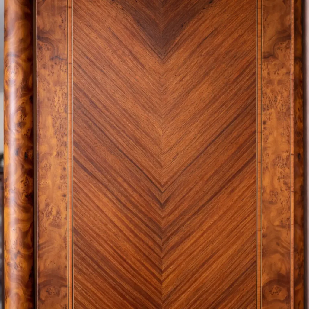 Elegante vetrina a un’anta in legno finemente impiallacciato in radica, con riserve e filettature a contrasto, riconducibile al gusto Luigi XVI / Neoclassico. Struttura architettonica con colonne laterali e anta a vetro originale, arricchita da ricche applicazioni in bronzo dorato: fregio floreale al coronamento, maniglia e guarnizioni finemente cesellate. Interni con ripiani destinati all’esposizione di porcellane. Manifattura francese o mitteleuropea, fine XIX – inizi XX secolo. Buono stato di conservazione, con patina coerente all’età e all’uso.