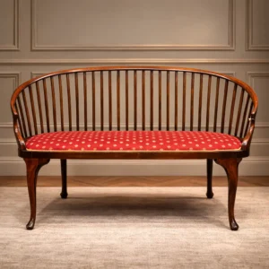 Elegante divanetto neoclassico a due posti, fine XVIII – inizi XIX secolo, in legno massello. Caratterizzato da schienale curvilineo a stecche verticali e braccioli integrati, presenta linee armoniose ed equilibrate di gusto sobrio e raffinato. Il sedile imbottito è rivestito in tessuto rosso decorato con piccoli motivi dorati e bordura in passamaneria, rifacimento successivo ma coerente. Struttura solida, bella patina originale e ottimo stato di conservazione. Mobile di grande eleganza e valore decorativo.