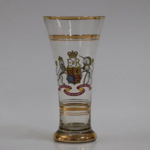 Bicchiere commemorativo in vetro trasparente, decorato con stemma reale britannico e iniziali E II R, realizzato per l’incoronazione della Regina Elisabetta II (1953). Arricchito da filettature dorate, testimonianza di produzione celebrativa d’epoca, di interesse storico e collezionistico.