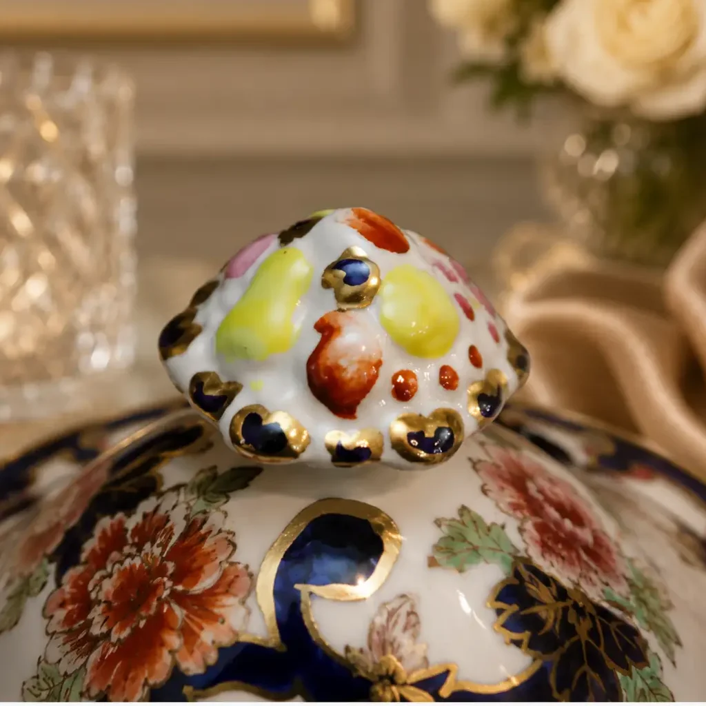 Zuppiera con coperchio in fine porcellana inglese Mason’s, linea Mandalay, decorata con ricco motivo floreale policromo, elementi in blu cobalto e abbondanti dorature. Forma mossa con prese laterali e presa sul coperchio modellata e dipinta. Marchio Mason’s al fondo. Produzione del XX secolo. Elegante oggetto da tavola e da collezione, in buono stato di conservazione.