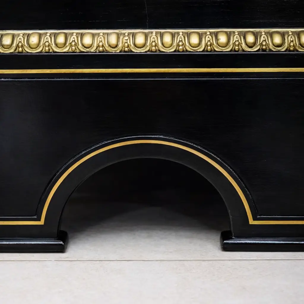 Vetrina alla Boulle in ebano, tartaruga e bronzi dorati Francia, seconda metà del XIX secolo – Stile Napoleone III Raffinata vetrina a un’anta realizzata secondo la celebre tecnica “alla Boulle”, con impiallacciatura in ebano e ricchi intarsi in ottone su fondo in tartaruga rossa naturale, disposti in eleganti motivi a racemi e volute di gusto Luigi XIV. Il prospetto è impreziosito da importanti applicazioni in bronzo dorato finemente cesellato, raffiguranti figure allegoriche laterali, fregi a foglie d’acanto e mascherone centrale nella parte inferiore. L’anta vetrata, incorniciata da profili dorati, apre su ripiani interni destinati all’esposizione di porcellane e oggetti d’arte. Esempio di alta ebanisteria francese del periodo Napoleone III, il mobile coniuga ricchezza ornamentale, equilibrio architettonico e forte impatto scenografico, risultando ideale per ambienti di rappresentanza o collezioni antiquarie di pregio.