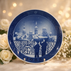 Piatto da parete in porcellana Royal Copenhagen, serie natalizia “Jul på Slottet / Christmas at the Manor House”, datato 1988. Decorazione blu cobalto sottosmalto con veduta invernale di città e figure di bambini affacciati a una balaustra, entro ampia tesa decorata con motivi stilizzati e data in rilievo. Marchio verde al verso con corona e scritta Royal Copenhagen Denmark. Manifattura danese del XX secolo, ottimo stato di conservazione, oggetto da collezione.