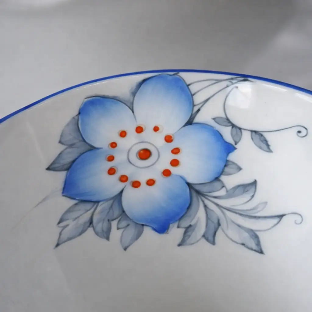 Trio da tè in porcellana inglese Bell China composto da tazza, piattino e piatto dessert, decorato con motivi floreali policromi in azzurro e giallo e bordo blu cobalto. Produzione Inghilterra, prima metà del Novecento. In buone condizioni, ideale per collezione o uso elegante.