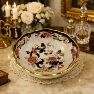 Centrotavola in porcellana Mason’s “Mandalay” Elegante centrotavola in porcellana Ironstone Mason’s, modello Mandalay, produzione inglese del Novecento. Caratterizzato da forma mossa con bordo ondulato rifinito in oro, presenta una ricca decorazione policroma di gusto orientaleggiante con grandi motivi floreali nei toni del rosa, arancio e giallo, intrecciati a volute blu cobalto impreziosite da dettagli dorati. Il piede sagomato riprende il medesimo apparato ornamentale, conferendo equilibrio e continuità decorativa all’insieme. Smalto brillante, colori vividi e dorature ben conservate ne esaltano la qualità esecutiva. In ottimo stato di conservazione, ideale come raffinato elemento da centro tavola o da esposizione. Misura: diametro cm. 28