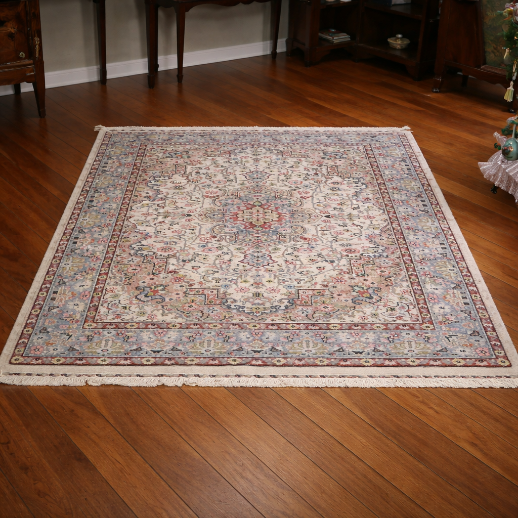 Elegante tappeto orientale di manifattura persiana, annodato a mano in lana su ordito in cotone, caratterizzato da un armonioso medaglione centrale su campo avorio riccamente decorato da motivi floreali e vegetali stilizzati. La composizione è racchiusa da una raffinata bordura a fondo azzurro-grigio con decori policromi coordinati. La palette cromatica, nei toni dell’avorio, rosa, azzurro, celeste e rosso mattone, dona luminosità e delicatezza all’insieme. Il tappeto si presenta in ottimo stato di conservazione, con vello compatto e colori ben conservati. Ideale per valorizzare salotti, studi o ambienti classici. Dimensioni: cm 190 x 130