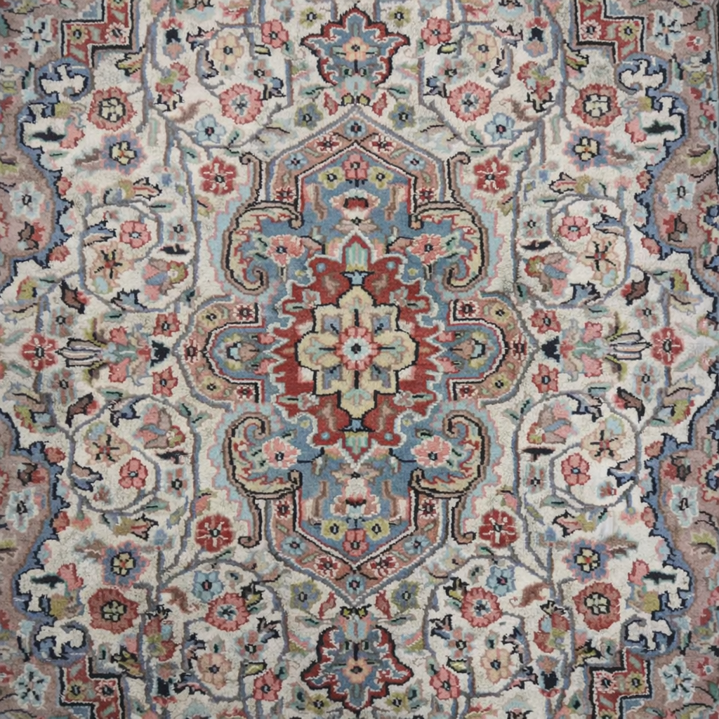 Elegante tappeto orientale di manifattura persiana, annodato a mano in lana su ordito in cotone, caratterizzato da un armonioso medaglione centrale su campo avorio riccamente decorato da motivi floreali e vegetali stilizzati. La composizione è racchiusa da una raffinata bordura a fondo azzurro-grigio con decori policromi coordinati. La palette cromatica, nei toni dell’avorio, rosa, azzurro, celeste e rosso mattone, dona luminosità e delicatezza all’insieme. Il tappeto si presenta in ottimo stato di conservazione, con vello compatto e colori ben conservati. Ideale per valorizzare salotti, studi o ambienti classici. Dimensioni: cm 190 x 130