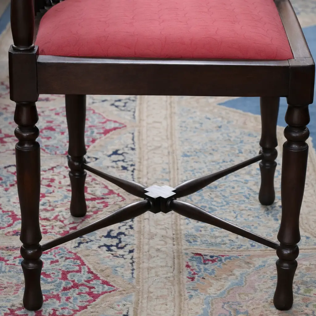 Elegante poltroncina inglese ad angolo di gusto vittoriano, realizzata in legno massello con raffinato schienale curvo a colonnine tornite disposto a ventaglio. La particolare struttura avvolgente richiama i celebri modelli Corner Chair inglesi, apprezzati per comfort ed eleganza negli ambienti signorili tra Otto e Novecento. La seduta imbottita, rivestita in tessuto rosso damascato, crea un piacevole contrasto con la calda tonalità del legno. Le gambe tornite unite da traverse incrociate sagomate conferiscono stabilità e armonia alla struttura.