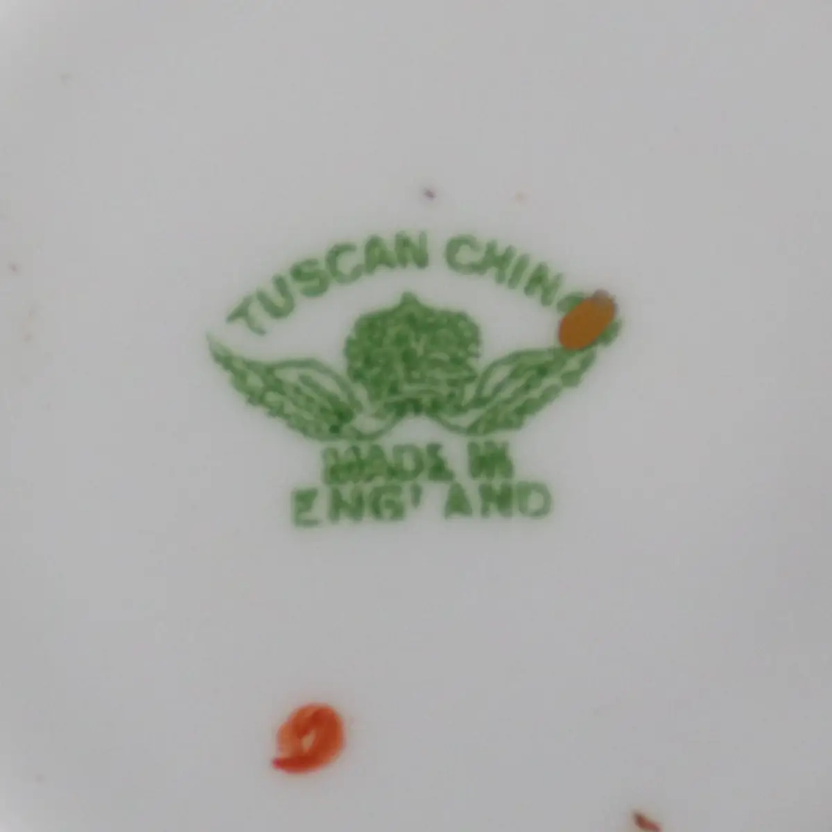 TUSCAN CHINA – Longton, Staffordshire Trio da tè in porcellana fine, ca. 1930–1950 Raffinato trio da tè composto da tazza, piattino e piatto dessert coordinato, in porcellana inglese di produzione Tuscan China, con marchio al verso in verde “Tuscan China – Made in England”. La decorazione, di gusto Imari reinterpretato, presenta motivi floreali e volute stilizzate in rosso ferro e blu cobalto, impreziosite da tocchi in verde e ricche profilature in oro zecchino. Il piatto è elegantemente sagomato con angoli arrotondati e bordo dorato; la tazza, leggermente svasata, è dotata di ansa sagomata con filettatura in oro. Esemplare di grande impatto cromatico e qualità esecutiva, in ottimo stato di conservazione con minimi e fisiologici segni del tempo. Ideale per collezionisti di porcellane inglesi del Novecento o per una mise en place di gusto classico ed elegante.