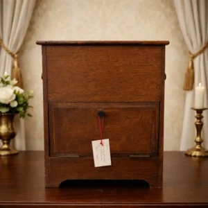 Porta carbone inglese vittoriano della seconda metà del XIX secolo, in legno massello con patina originale. Dotato di coperchio incernierato, sportello frontale ribaltabile e interno con rivestimento metallico. Pezzo autentico d’epoca, sobrio ed elegante, ideale come complemento accanto al camino o come contenitore decorativo.