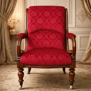 Poltrona Regency inglese in noce, primo quarto XIX secolo Elegante poltrona da conversazione di manifattura inglese, databile al periodo Regency (circa 1815–1835), realizzata in massello di noce con struttura finemente sagomata e seduta imbottita. La linea è caratterizzata da braccioli a voluta continua che si raccordano armoniosamente allo schienale inclinato, creando una silhouette fluida e ben proporzionata. Le gambe anteriori tornite, complete di ruotine originali, testimoniano l’originaria destinazione d’uso come seduta da salotto facilmente movimentabile. La poltrona è rivestita in velluto damascato rosso rubino a motivo floreale, che valorizza il carattere aristocratico del mobile e contrasta piacevolmente con la calda tonalità del noce. Il legno conserva una bella patina antica, segno di autenticità e buona conservazione. Arredo raffinato e confortevole, ideale per ambienti classici, studi, biblioteche o salotti di rappresentanza.