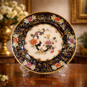 Piatto da collezione “The Mason’s Royal Mandalay” – Edizione Limitata n. 304/750 Mason’s Ironstone, Inghilterra, 2000 Elegante piatto celebrativo in ironstone appartenente alla prestigiosa serie “The Mason’s Royal Mandalay”, realizzata in tiratura limitata di soli 750 esemplari in occasione del Millennio. L’esemplare proposto è numerato 304/750, come da marchio al verso. La decorazione si distingue per il raffinato fondo blu cobalto intenso arricchito da ampie lumeggiature in oro e motivi floreali policromi nei toni del rosso, rosa e verde, secondo il celebre gusto orientaleggiante della tradizione Mason’s. Il cavetto centrale presenta un elegante motivo “Mandalay” armoniosamente incorniciato da volute dorate. In eccellente stato di conservazione, è un oggetto di forte impatto decorativo, ideale per collezionisti di Mason’s Ironstone o come piatto da parata in ambienti classici ed eleganti.