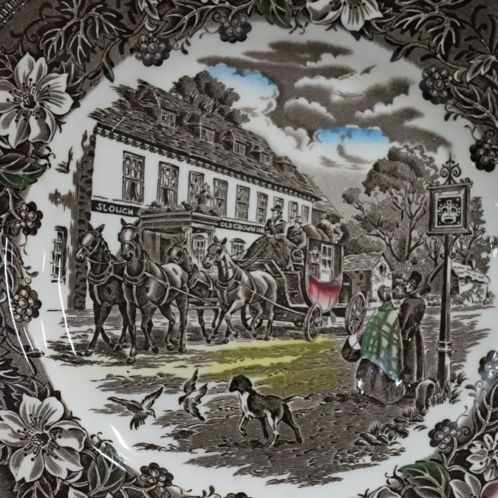Importante servizio da tavola inglese Royal Tudor Ware – Staffordshire, decoro “Coaching Taverns 1828”, con incisione firmata W.N. Mellor. Realizzato in terraglia fine con stampa sottosmalto nei toni seppia arricchiti da delicati tocchi policromi, presenta suggestive scene di diligenze e locande inglesi incorniciate da un’elegante bordura floreale. Il servizio è composto da 41 pezzi: 12 piatti piani, 12 fondi, 12 piatti antipasto, 1 piatto da portata tondo, 2 piatti da portata ovale, 1 zuppiera con coperchio e 1 insalatiera.
