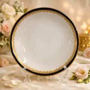 Piatto in porcellana inglese Collingwood, marchiato Collingwood – Made in England, decorato con elegante bordo blu scuro e fine greca dorata interna a motivo continuo. Linea sobria ed equilibrata, di gusto classico. Produzione prima metà del XX secolo. In buone condizioni generali, con lievi segni del tempo. Adatto a collezione o utilizzo