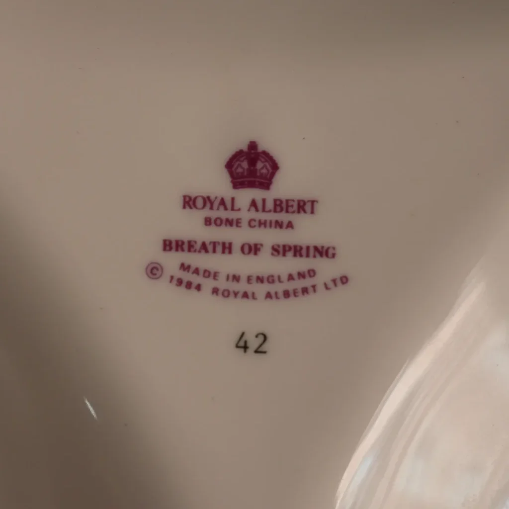Royal Albert “Breath of Spring” – Piatto da dolce a trifoglio Delizioso piatto da dolce a forma di trifoglio della celebre collezione Breath of Spring di Royal Albert, realizzato in pregiata Bone China inglese. La particolare forma trilobata, con tre scomparti e raffinato manico centrale, lo rende un oggetto originale e ricercato, perfetto per presentare con eleganza pasticcini, biscotti, confetti e piccole prelibatezze. La delicata decorazione floreale nei toni del rosa, impreziosita da profilature dorate e raffinati rilievi ornamentali, dona alla porcellana un fascino romantico e tipicamente inglese. Un piccolo gioiello della tavola, capace di trasformare anche un semplice tè pomeridiano in un momento speciale. Perfetto da utilizzare, esporre o aggiungere a una collezione di porcellane Royal Albert. Royal Albert Bone China – Made in England – “Breath of Spring”. Un pezzo originale e pieno di charme, ideale per chi ama la raffinata eleganza delle porcellane inglesi.