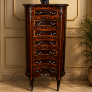 Settimino a fagiolo in stile Luigi XV Elegante settimino a fagiolo in stile Luigi XV, caratterizzato da una raffinata struttura sagomata e sinuosa, realizzata in noce e radica dalle calde tonalità naturali. Il fronte è composto da sette cassetti con andamento mosso, impreziositi da maniglie e applicazioni in bronzo dorato, che conferiscono al mobile un ricercato carattere decorativo. Il piano superiore, dalla linea sagomata, e le eleganti gambe arcuate completano la tipica impostazione rocaille, donando leggerezza e armonia all'insieme. Le dimensioni particolarmente contenute ne fanno un mobile versatile, ideale anche per ambienti raffinati di dimensioni ridotte. Dimensioni: L. 43 × P. 32 × H. 137 cm. Cassetti: dimensioni interne 30 × 24 × 10 cm.